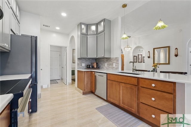 kitchen with arched walkways, stainless steel appliances, backsplash, brown cabinetry, and a peninsula