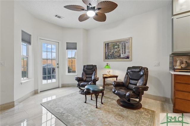 living area with ceiling fan and baseboards