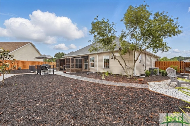 rear view of house featuring a sunroom, a fenced backyard, and a patio area