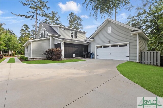 240 Blackjack Oak Dr W, Richmond Hill, GA 31324 - view of front of home featuring a garage, driveway, a front yard, and a sunroom