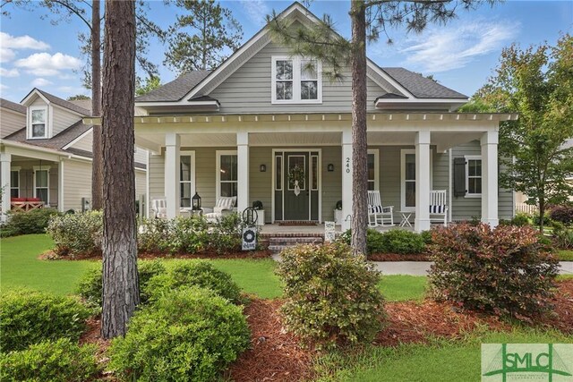 240 Blackjack Oak Dr W, Richmond Hill, GA 31324 - view of front facade with covered porch, a front lawn, and a shingled roof