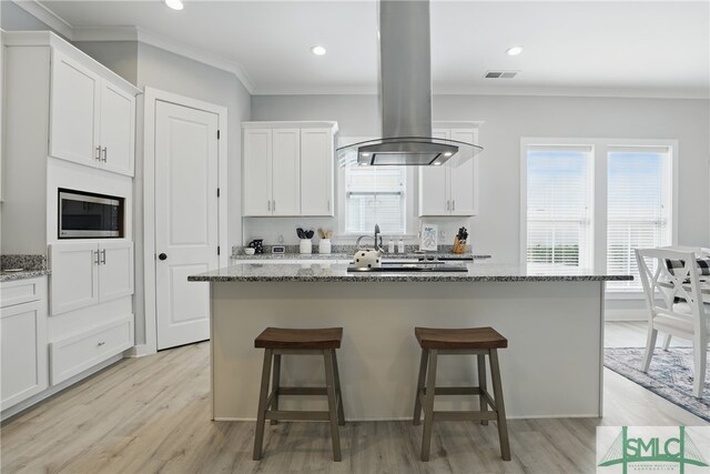 240 Blackjack Oak Dr W, Richmond Hill, GA 31324 - kitchen with stainless steel microwave, island range hood, a kitchen breakfast bar, light wood-style flooring, and crown molding
