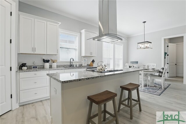 240 Blackjack Oak Dr W, Richmond Hill, GA 31324 - kitchen featuring a sink, black electric stovetop, light wood-type flooring, island range hood, and white cabinetry