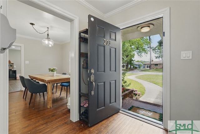foyer entrance with wood finished floors and crown molding