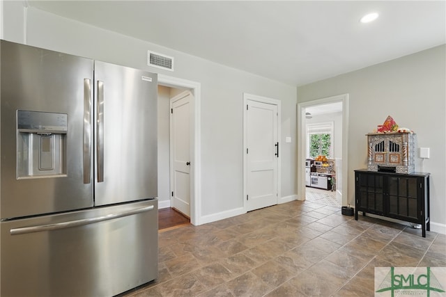 kitchen featuring stainless steel refrigerator with ice dispenser, stone finish flooring, baseboards, and recessed lighting