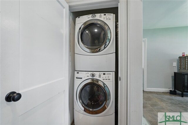 laundry room with estacked washer and dryer and baseboards