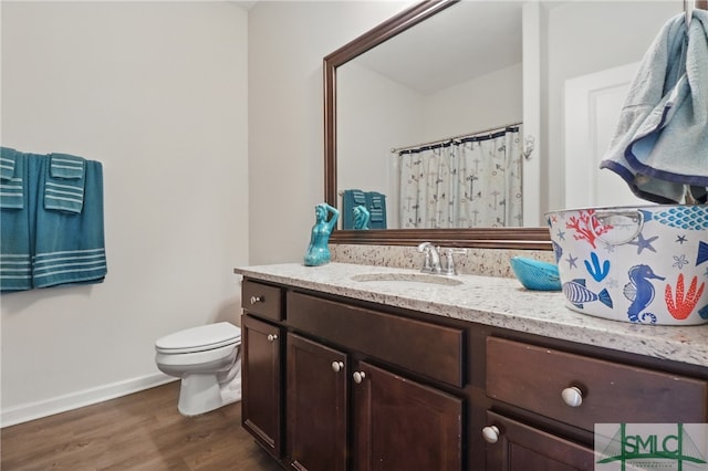 bathroom featuring wood finished floors, toilet, vanity, baseboards, and curtained shower