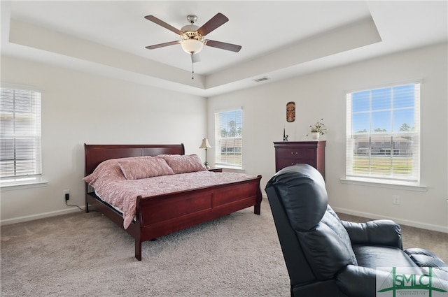 bedroom with a raised ceiling, carpet flooring, baseboards, and ceiling fan