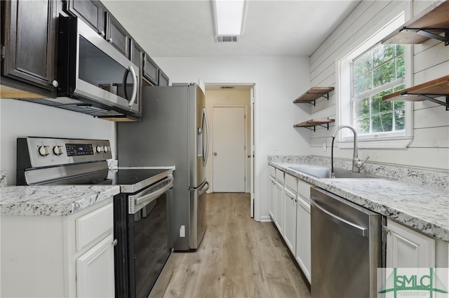 57 Cut Off Way, Richmond Hill, GA 31324 - kitchen featuring appliances with stainless steel finishes, a sink, open shelves, light wood finished floors, and white cabinetry
