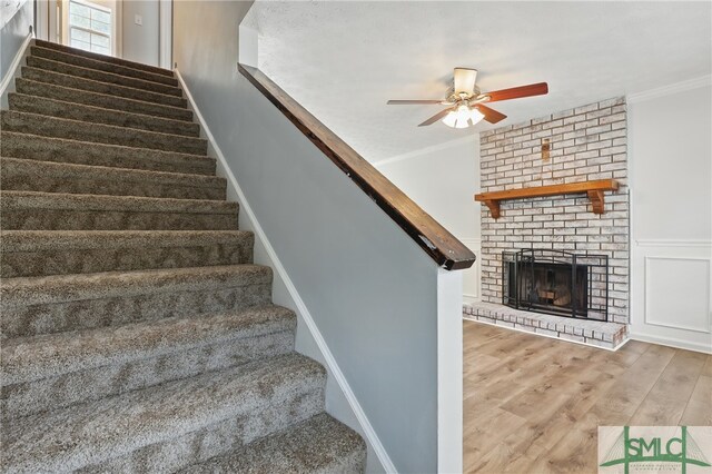 57 Cut Off Way, Richmond Hill, GA 31324 - staircase featuring ceiling fan, wood finished floors, crown molding, and a brick fireplace