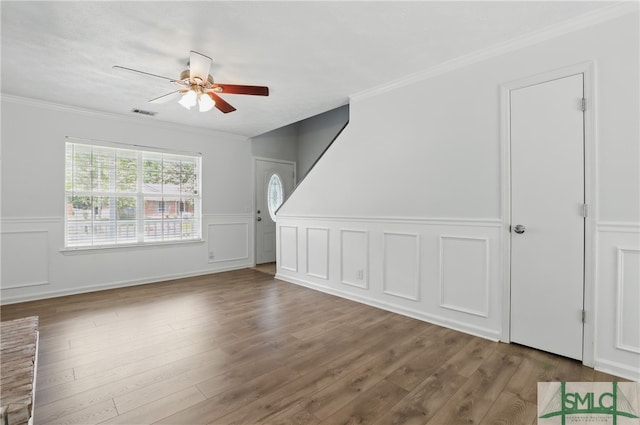 57 Cut Off Way, Richmond Hill, GA 31324 - unfurnished living room featuring a ceiling fan, a wainscoted wall, ornamental molding, wood finished floors, and a decorative wall