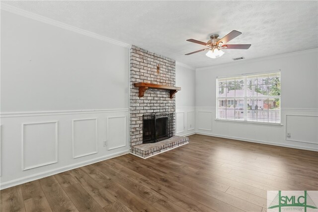 57 Cut Off Way, Richmond Hill, GA 31324 - unfurnished living room featuring a textured ceiling, a brick fireplace, ceiling fan, wood finished floors, and a decorative wall