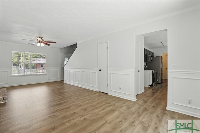 57 Cut Off Way, Richmond Hill, GA 31324 - unfurnished living room with ceiling fan, light wood finished floors, crown molding, a wainscoted wall, and a decorative wall