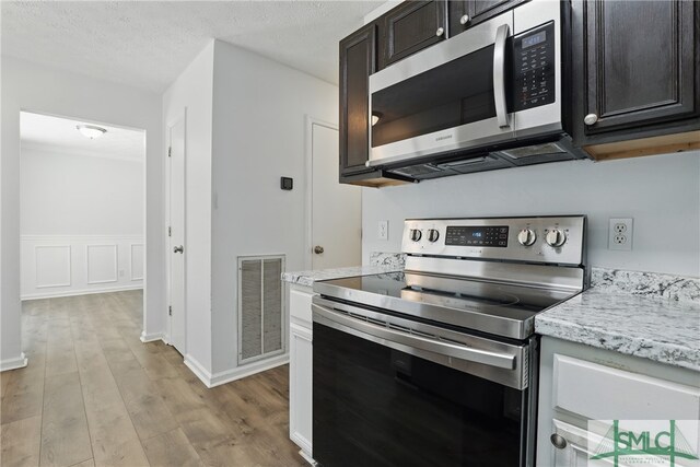 57 Cut Off Way, Richmond Hill, GA 31324 - kitchen featuring stainless steel appliances, light wood-style floors, dark brown cabinetry, a textured ceiling, and light stone counters