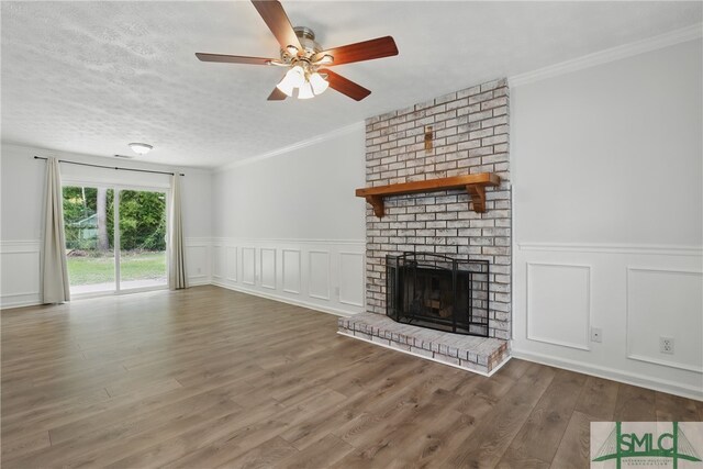 57 Cut Off Way, Richmond Hill, GA 31324 - unfurnished living room with a decorative wall, a fireplace, wood finished floors, a wainscoted wall, and a ceiling fan