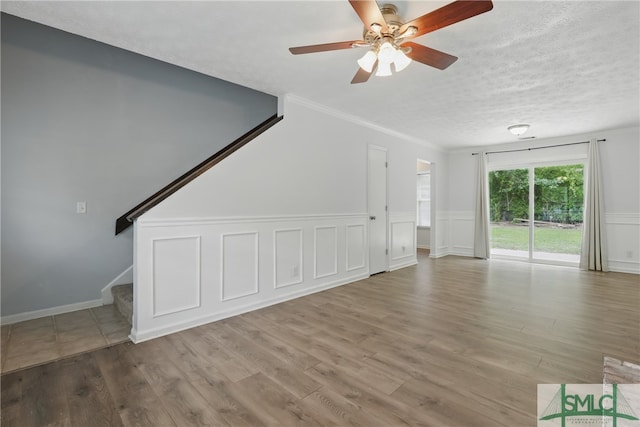 57 Cut Off Way, Richmond Hill, GA 31324 - unfurnished living room featuring stairway, a ceiling fan, wood finished floors, crown molding, and wainscoting