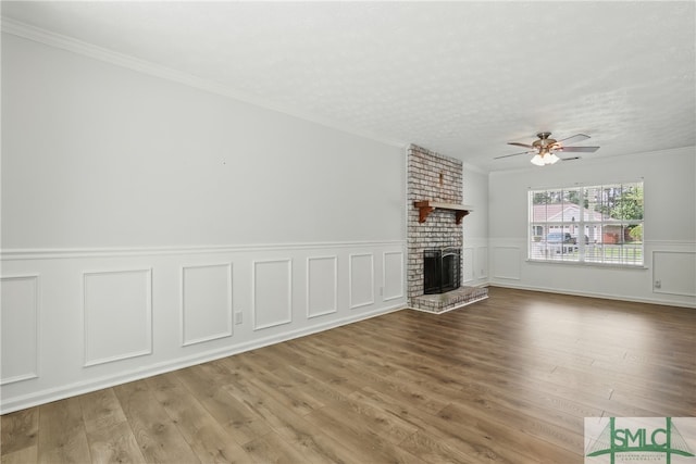 57 Cut Off Way, Richmond Hill, GA 31324 - unfurnished living room with a brick fireplace, a ceiling fan, ornamental molding, wood finished floors, and wainscoting