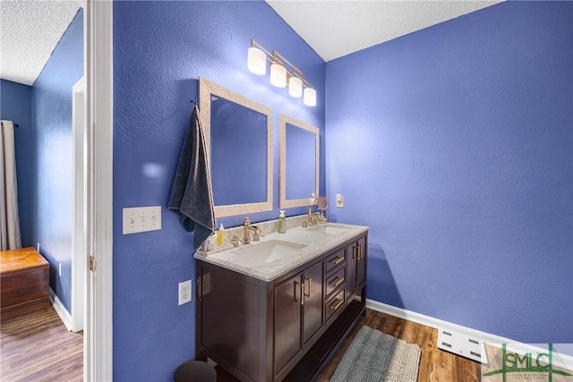 38 Travertine Cir, Savannah, GA 31419 - bathroom featuring wood finished floors, baseboards, a textured wall, double vanity, and a textured ceiling