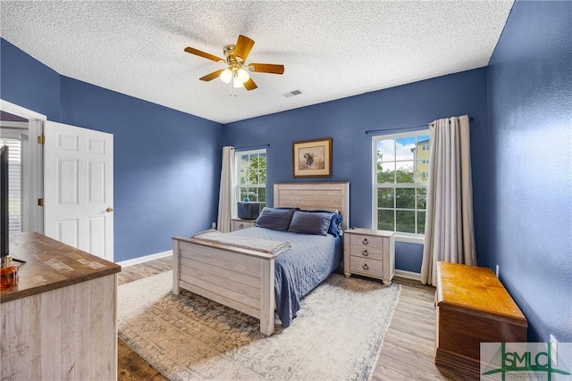 38 Travertine Cir, Savannah, GA 31419 - bedroom with light wood-type flooring, multiple windows, and a textured ceiling