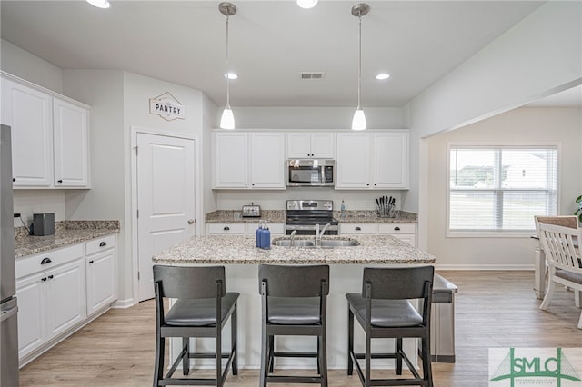 128 Greenbriar Dr, Guyton, GA 31312 - kitchen featuring appliances with stainless steel finishes, a sink, white cabinetry, a kitchen bar, and light wood-style floors