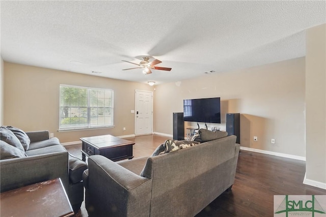 living room with a ceiling fan, dark wood-style floors, baseboards, and a textured ceiling