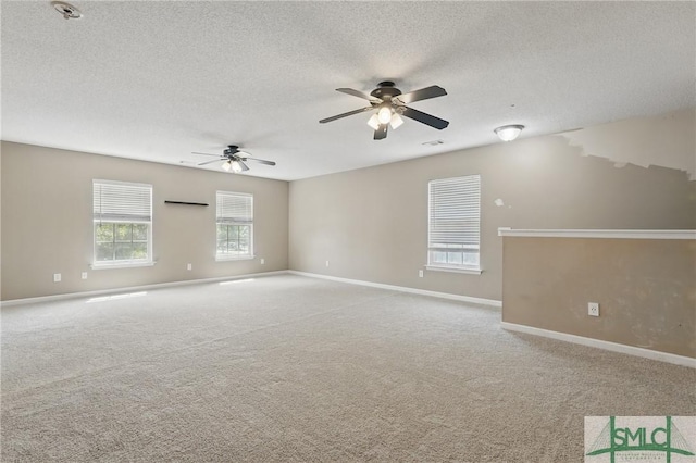 carpeted spare room with ceiling fan, baseboards, and a textured ceiling