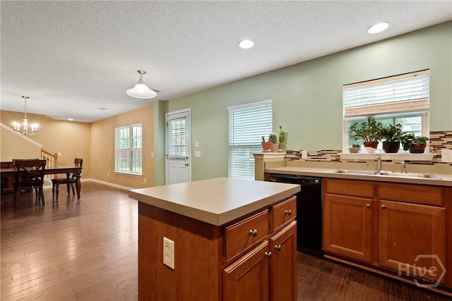 kitchen featuring a sink, dishwasher, brown cabinets, pendant lighting, and a textured ceiling
