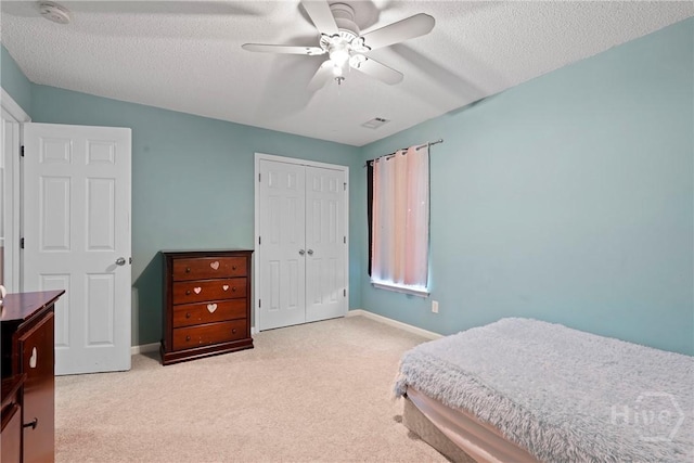 carpeted bedroom featuring a closet, a textured ceiling, baseboards, and ceiling fan