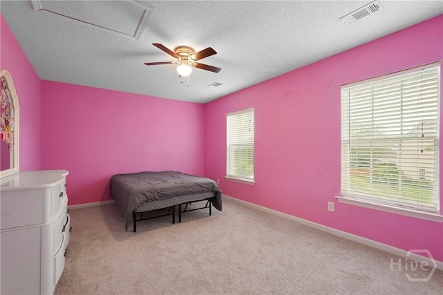 bedroom featuring light colored carpet, a textured ceiling, a ceiling fan, and baseboards
