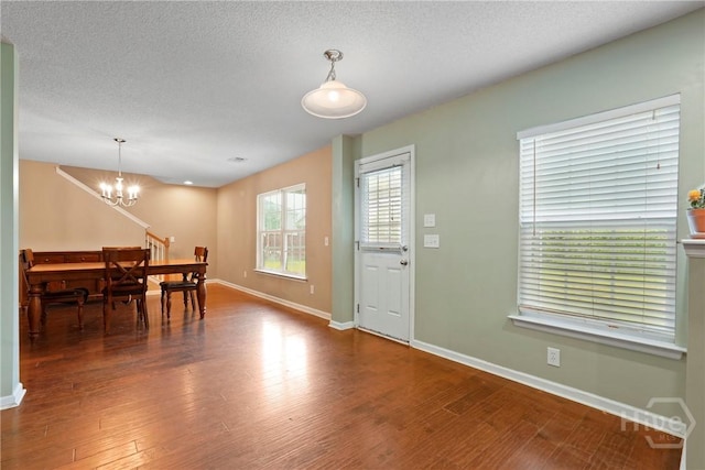 dining space with a chandelier, baseboards, wood finished floors, and a textured ceiling