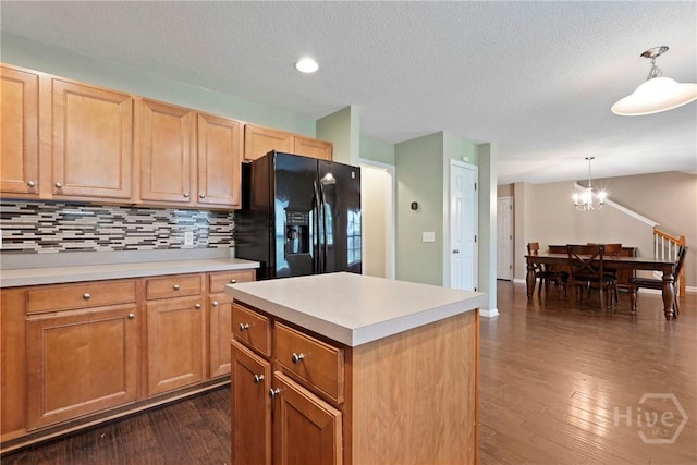 kitchen featuring black refrigerator with ice dispenser, dark wood-style floors, a chandelier, light countertops, and backsplash