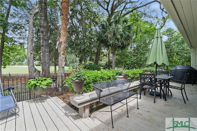 deck featuring grilling area, outdoor dining space, and view of scattered trees