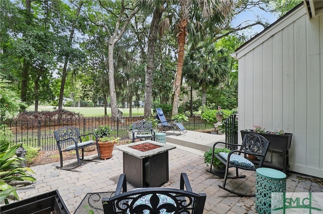 view of patio / terrace featuring an outdoor fire pit, fence, and view of wooded area