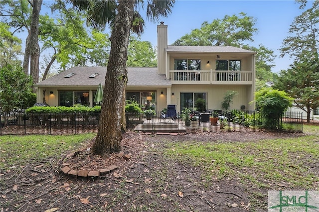 rear view of house featuring a balcony, a chimney, fence, and a patio