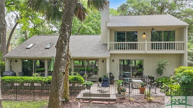 back of house featuring a patio area, a shingled roof, fence, and a balcony