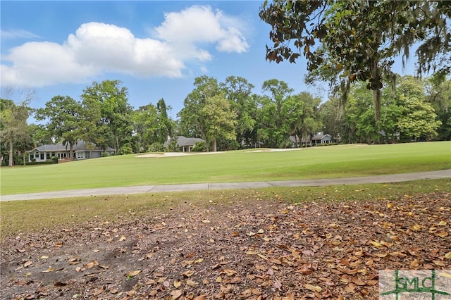 view of home's community featuring golf course view, a lawn, and view of wooded area
