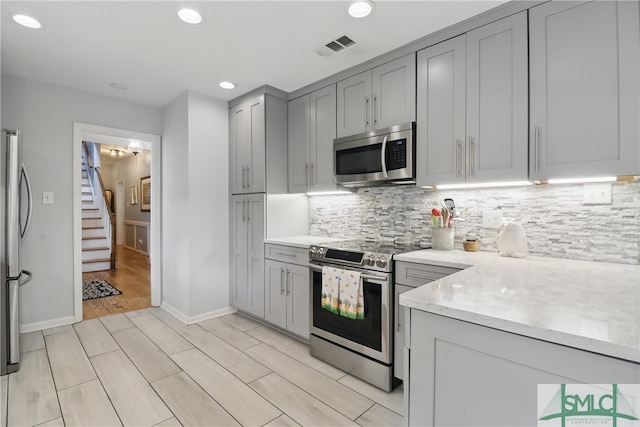 kitchen featuring stainless steel appliances, gray cabinets, light countertops, tasteful backsplash, and recessed lighting