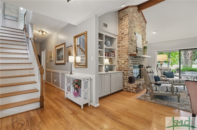 stairway with vaulted ceiling, wood finished floors, and a fireplace