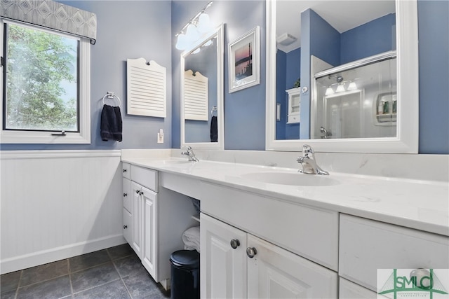 full bathroom featuring a shower stall, double vanity, wainscoting, and tile patterned floors