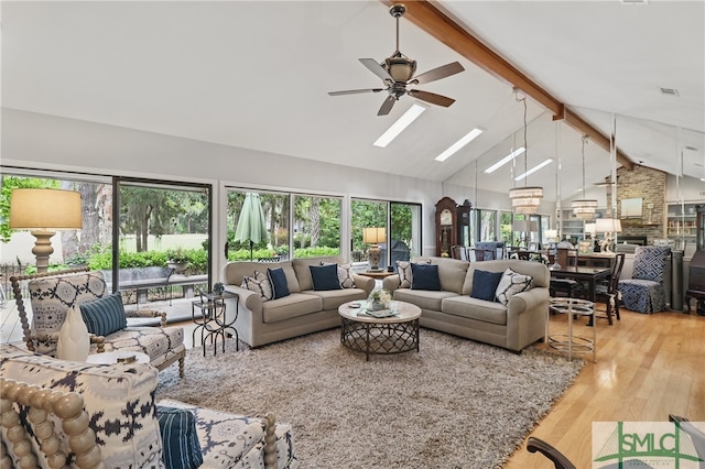 living area featuring a ceiling fan, beam ceiling, a skylight, wood finished floors, and healthy amount of natural light