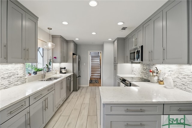 kitchen with gray cabinets, appliances with stainless steel finishes, a sink, recessed lighting, and backsplash
