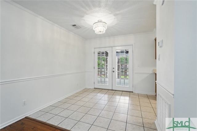 spare room featuring french doors, light tile patterned flooring, a chandelier, ornamental molding, and baseboards