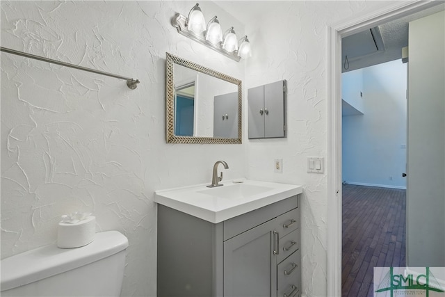 half bathroom with toilet, vanity, and wood finished floors