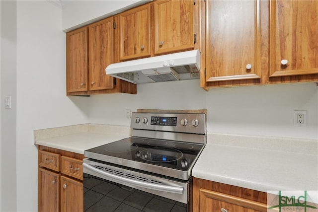 kitchen featuring stainless steel electric stove, under cabinet range hood, tile patterned floors, light countertops, and brown cabinets