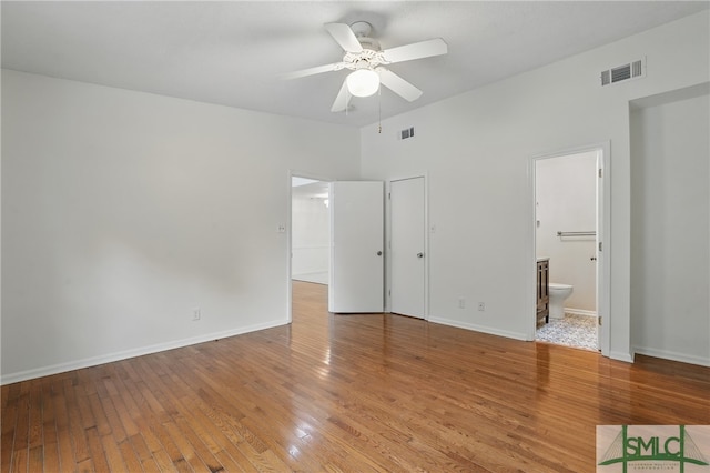 unfurnished bedroom featuring light wood finished floors, baseboards, ensuite bath, and a ceiling fan