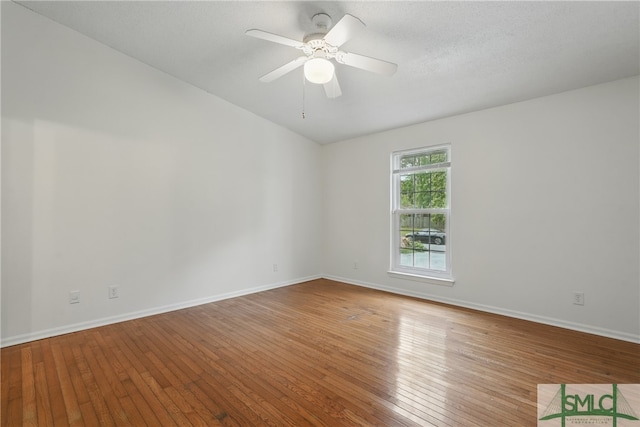 spare room featuring hardwood / wood-style floors, baseboards, and a ceiling fan