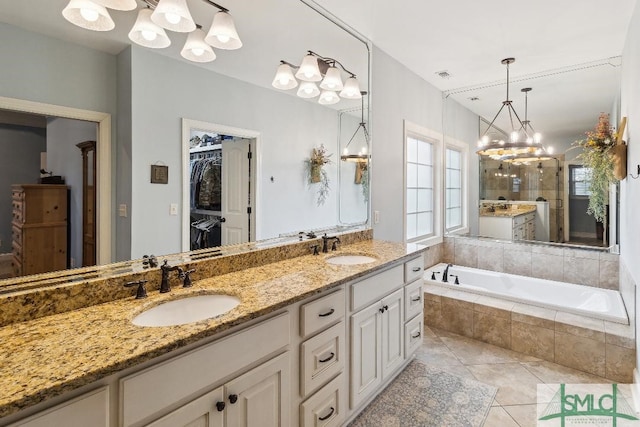 4 Honeysuckle Dr, Claxton, GA 30417 - bathroom with a chandelier, double vanity, a bath, tile patterned floors, and a walk in closet