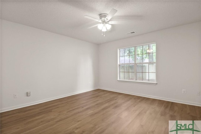 spare room with wood finished floors, a ceiling fan, a textured ceiling, and baseboards