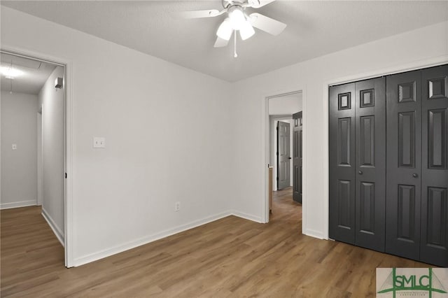 unfurnished bedroom with attic access, wood finished floors, baseboards, and a closet
