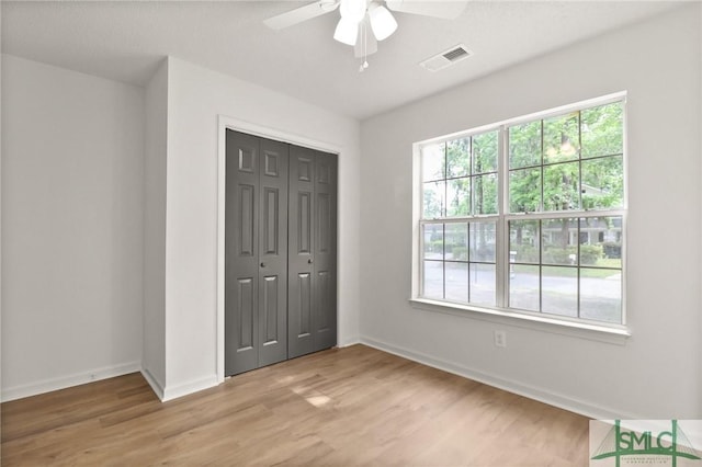 unfurnished bedroom featuring light wood-type flooring, baseboards, and a closet